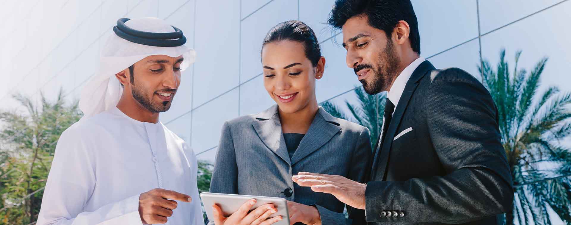 Three businesspeople in discussion around a tablet