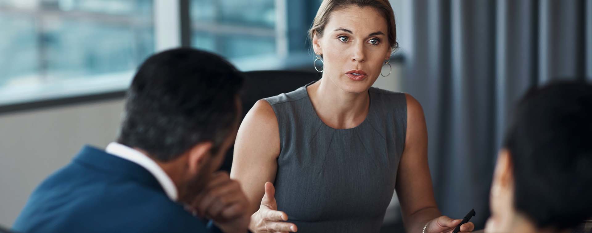 Businesswoman talking to two men in a boardroom