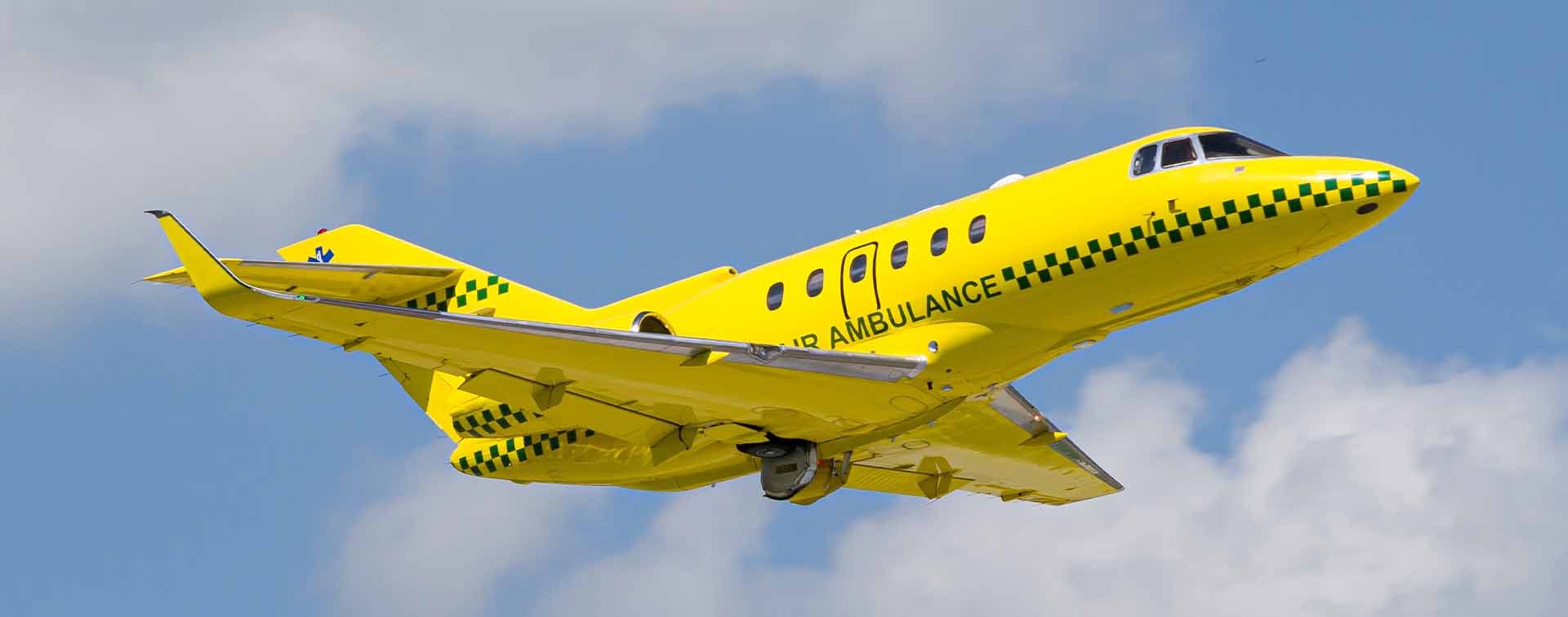 A yellow fixed-wing air ambulance aircraft similar to a Learjet 35A in flight