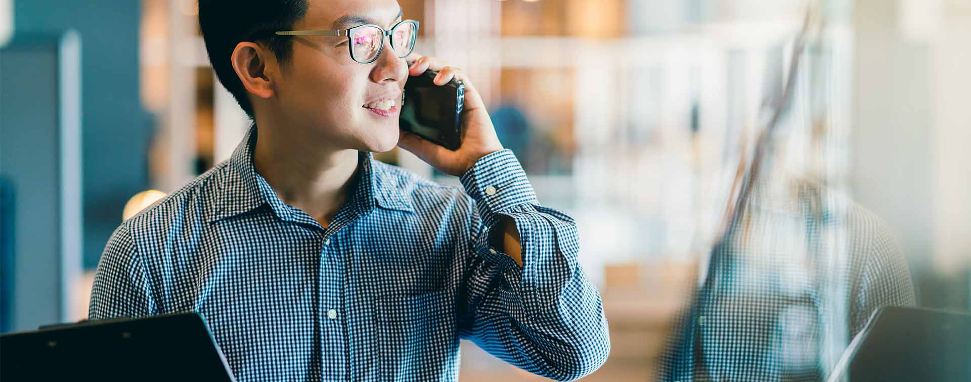 Asian male startup entrepreneur in office on a call