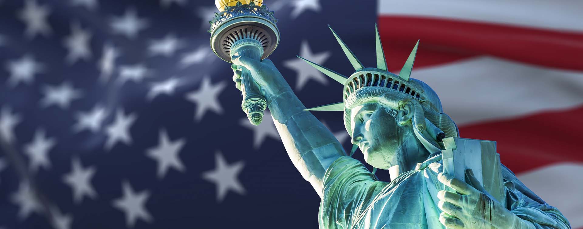The statue of liberty with blurry American flag waving in the background