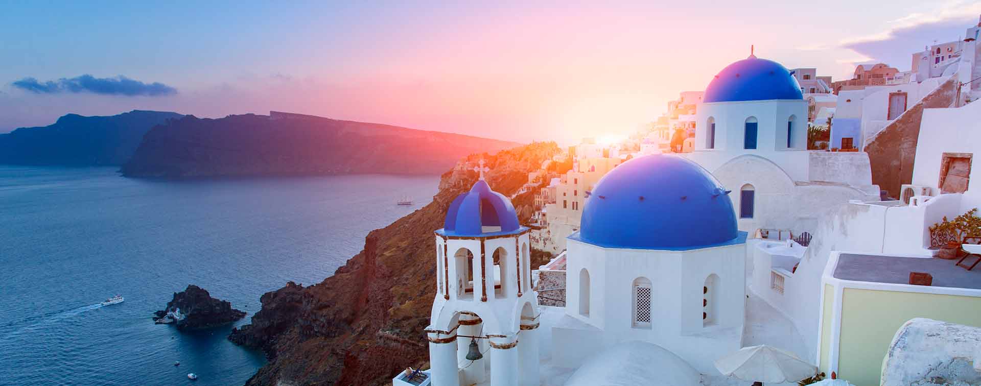 Blue domed churches at sunset in Oia, Santorini