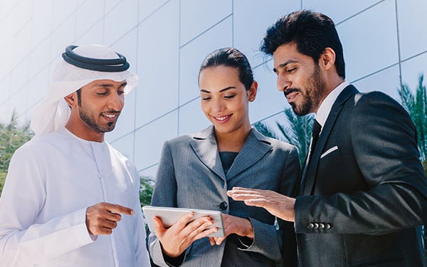 Three businesspeople in discussion around a tablet