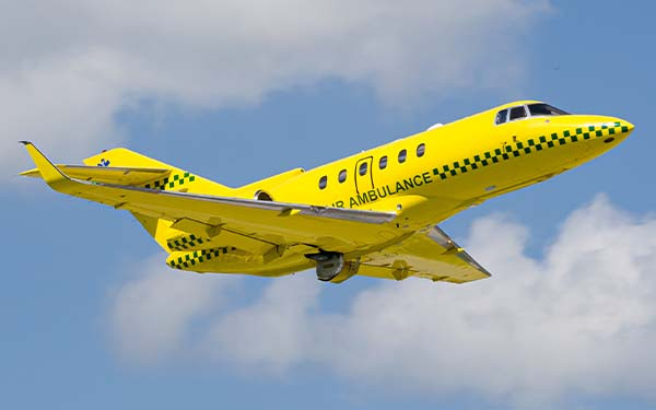A yellow fixed-wing air ambulance aircraft similar to a Learjet 35A in flight