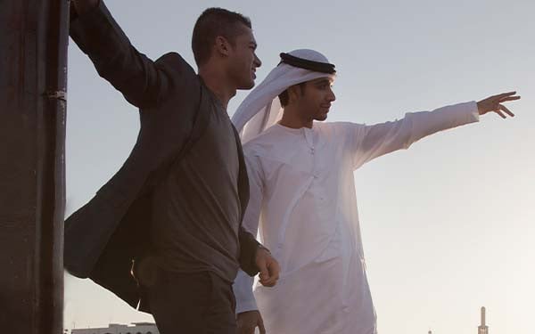 Two men looking out with the one pointing at something out in the distance.