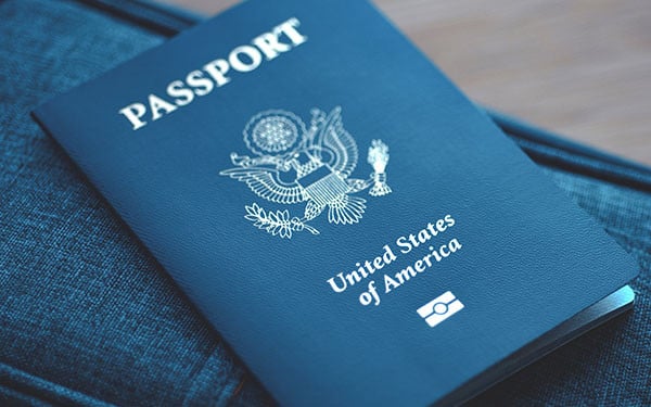 US passport on a blue travel bag against a wooden floor