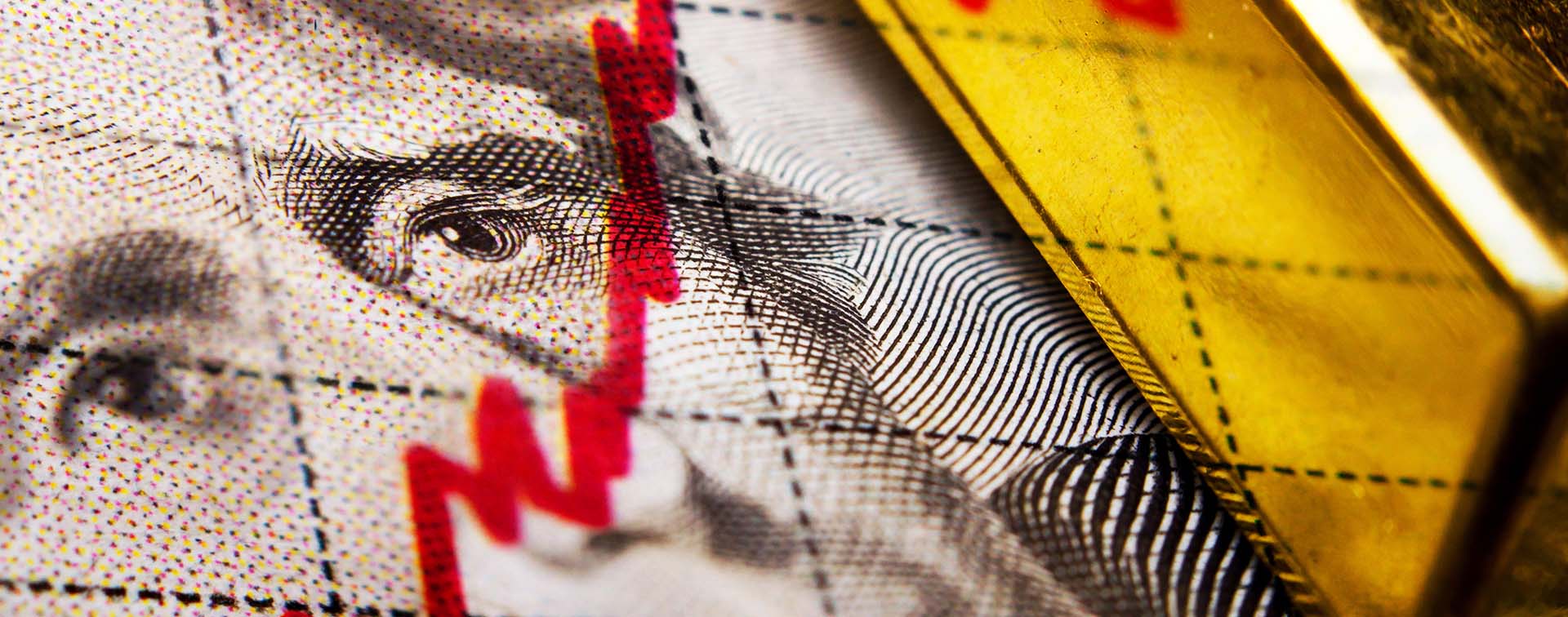 Close up of a dollar banknote and gold ingot and a financial chart