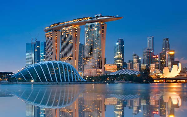 Gardens by the Bay and Singapore skyline reflection on blue water at blue hour in Singapore