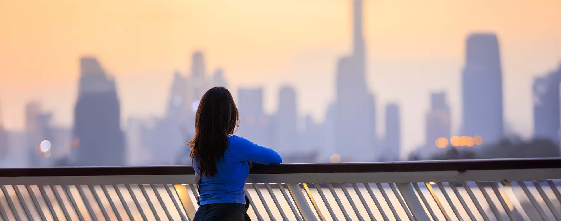 Young woman overlooking Dubai skyline during sunset.