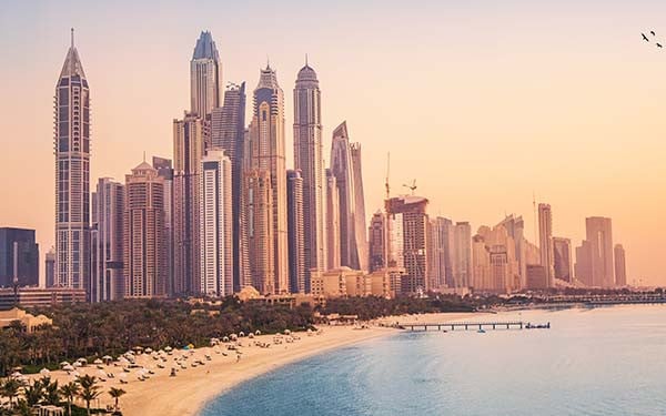 Sunset view of Dubai Marina and Jumira Beach Residence area with ferris wheel and golden sand beaches in the Persian Gulf