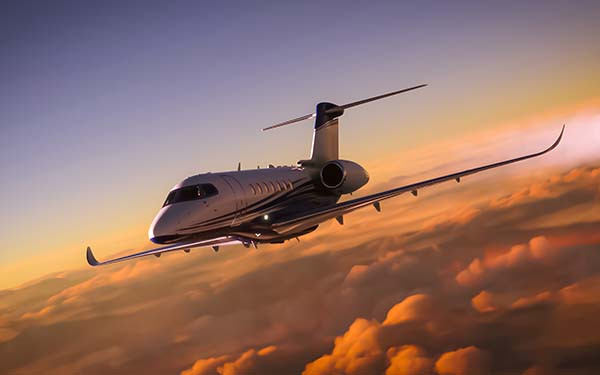 A luxury private jet overflying cloudy skies at sunset